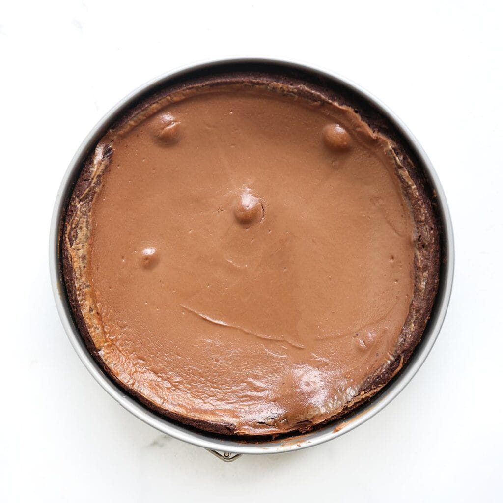 Zet de brownie-chocoladecheesecake in een voorverwarmde oven op 160 ℃. Bak 40-45 minuten, of tot de zijkanten stevig zijn en het midden nog licht wiebelt. Zet de oven uit en laat 1 uur in de oven staan om scheuren te voorkomen. Laat daarna volledig afkoelen. Zet afgedekt in de koelkast, het liefst een nachtje.