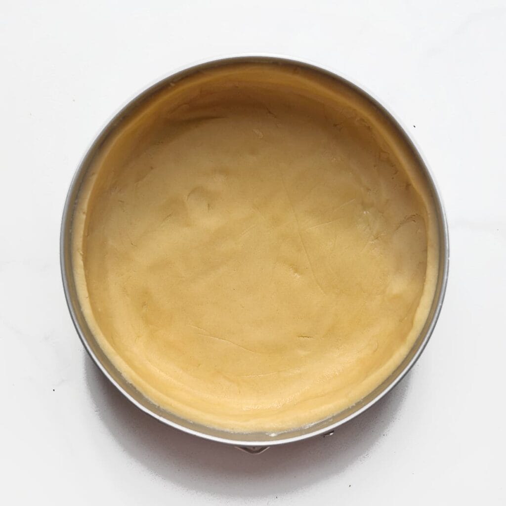 Bekleed de bodem en randen van de vorm met het deeg en druk goed aan (tip: gebruik de achterkant van een lepel). Zet de vorm met deeg even in de koelkast.